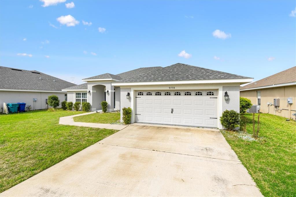 A single-story house with a white garage door, concrete driveway, and a grassy lawn — 9778 PEPPER TREE PLACE, WILDWOOD, FL