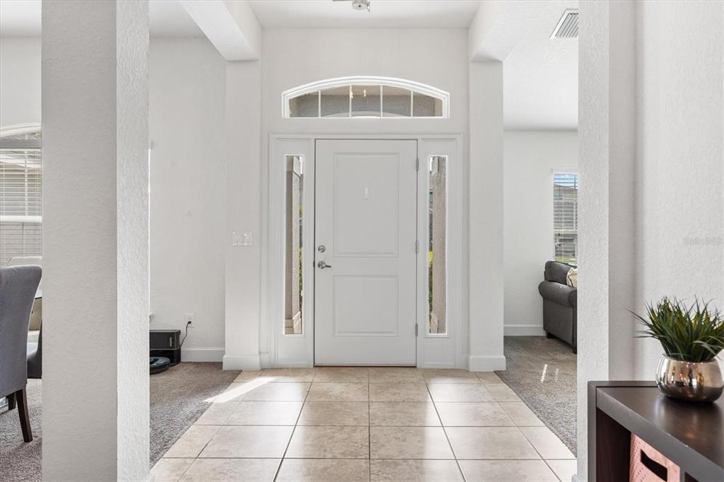 A tiled entryway features a white front door with sidelights and an arched transom window — 9778 PEPPER TREE PLACE, WILDWOOD, FL