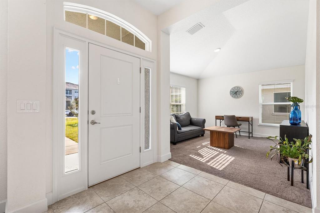 An entryway with tile flooring leads into a carpeted living area with a desk — 9778 PEPPER TREE PLACE, WILDWOOD, FL