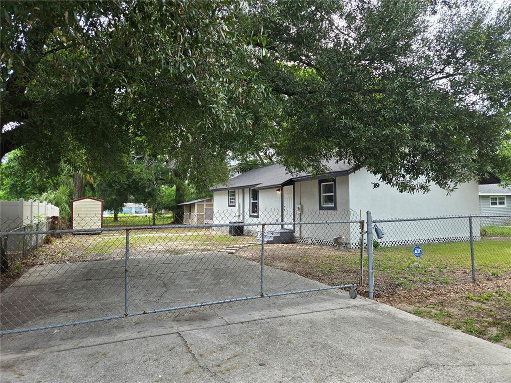 A single-story house with a white exterior, a chain-link fence, and a concrete driveway — 9408 N 12TH STREET, TAMPA, FL