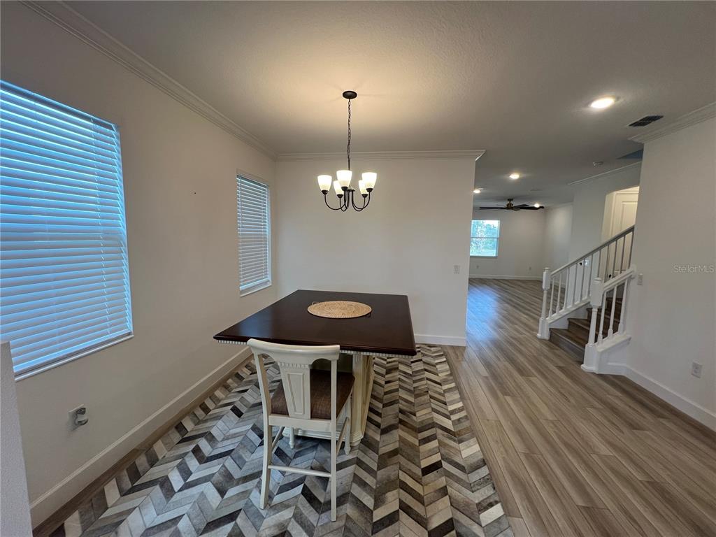 A dining area features a dark wood table, a patterned rug, and a staircase — 931 SIGNET DRIVE, APOLLO BEACH, FL