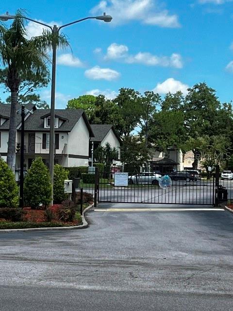 A gated entrance leads to multi-story residential buildings with a palm tree and street lamp — 600 NORTHERN WAY UNIT 1108, WINTER SPRINGS, FL