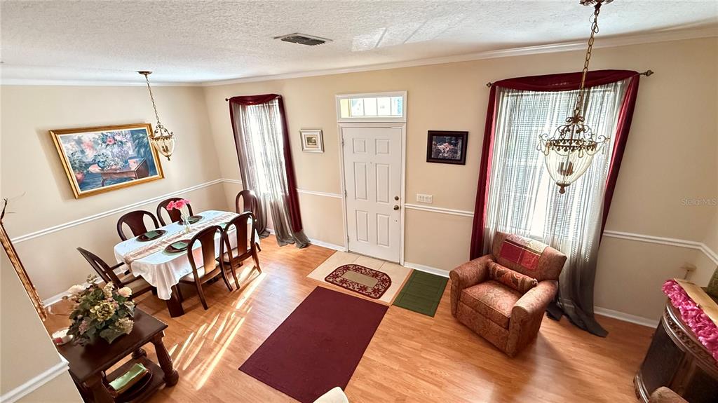 A dining area and entryway feature wood-look flooring, a chandelier, and a patterned armchair — 4670 CAPITAL BOULEVARD, ST CLOUD, FL