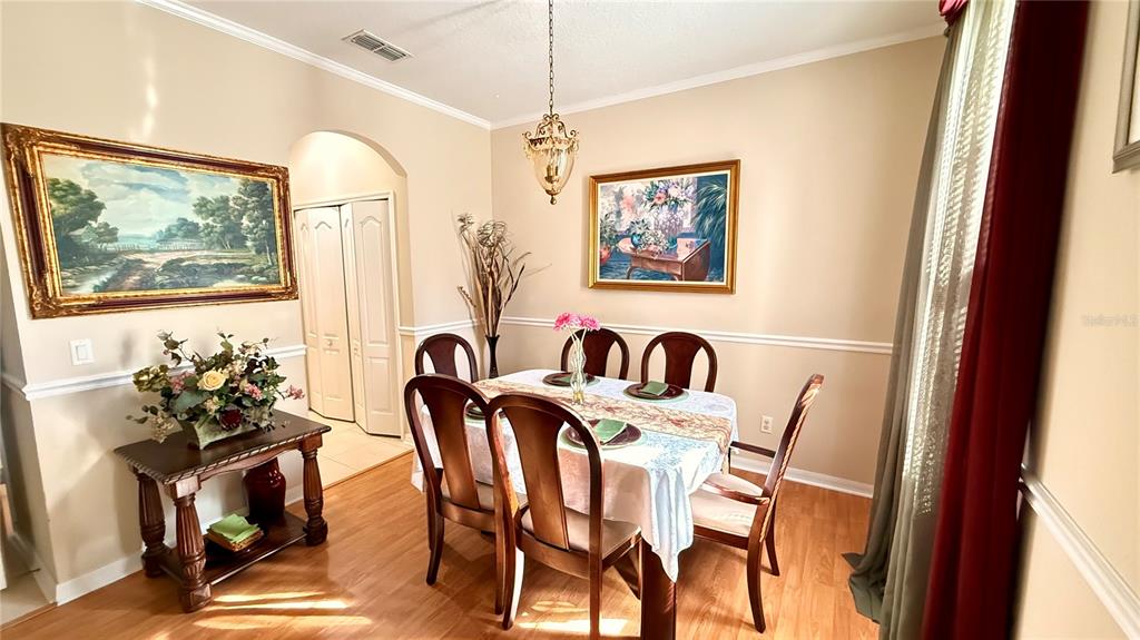 A dining room features a wooden table with six chairs, a chandelier, and wall art — 4670 CAPITAL BOULEVARD, ST CLOUD, FL