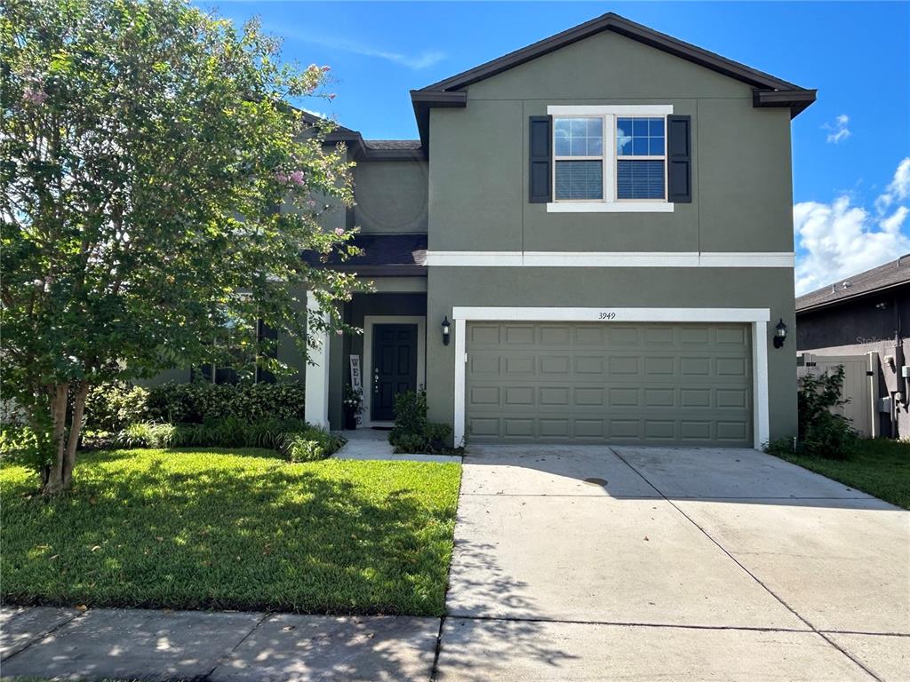 A two-story house with a green stucco exterior, a two-car garage, and a front lawn — 3949 BAJA DRIVE, ST CLOUD, FL