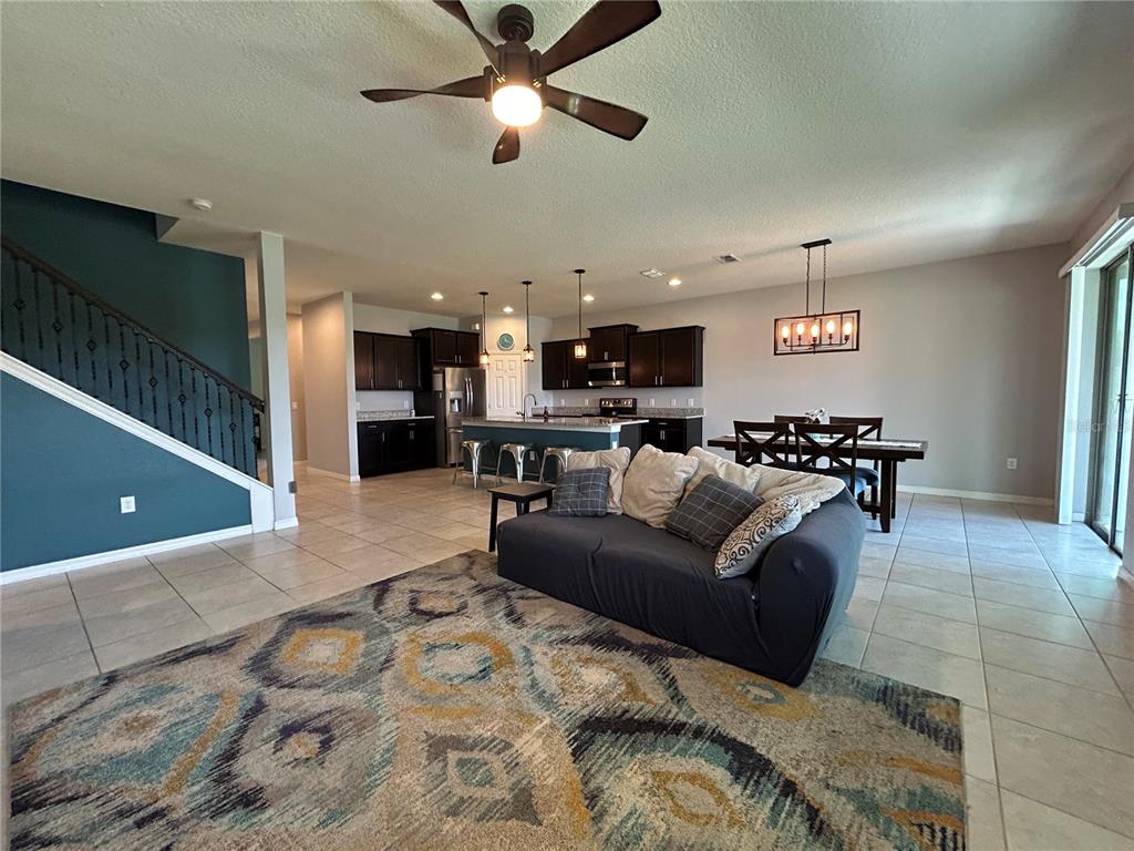 An open-concept living and dining area features dark wood cabinets, tile flooring, and a staircase — 3949 BAJA DRIVE, ST CLOUD, FL