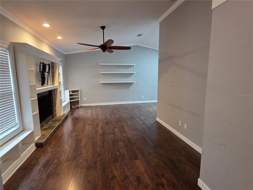 A living room features dark wood flooring, a fireplace, floating shelves, and a ceiling fan — 1033 ROSETREE LANE, TARPON SPRINGS, FL