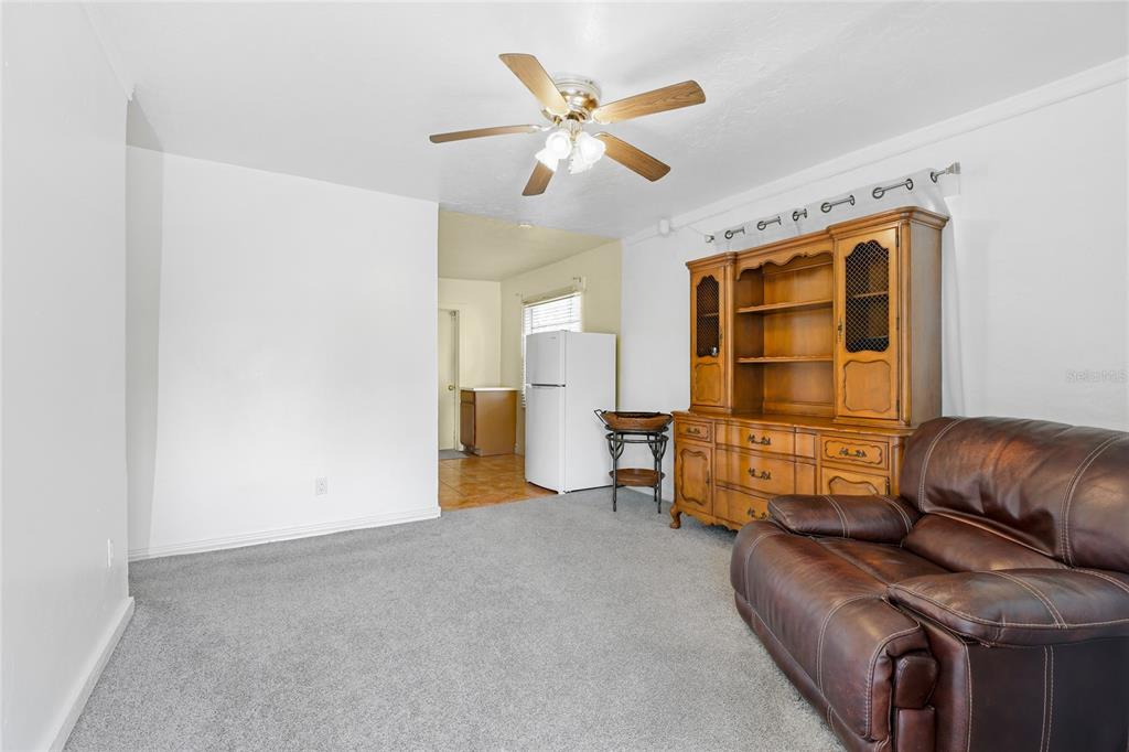 A living room features gray carpeting, a ceiling fan, a wooden hutch, and a leather recliner — 1598 29TH STREET, SARASOTA, FL