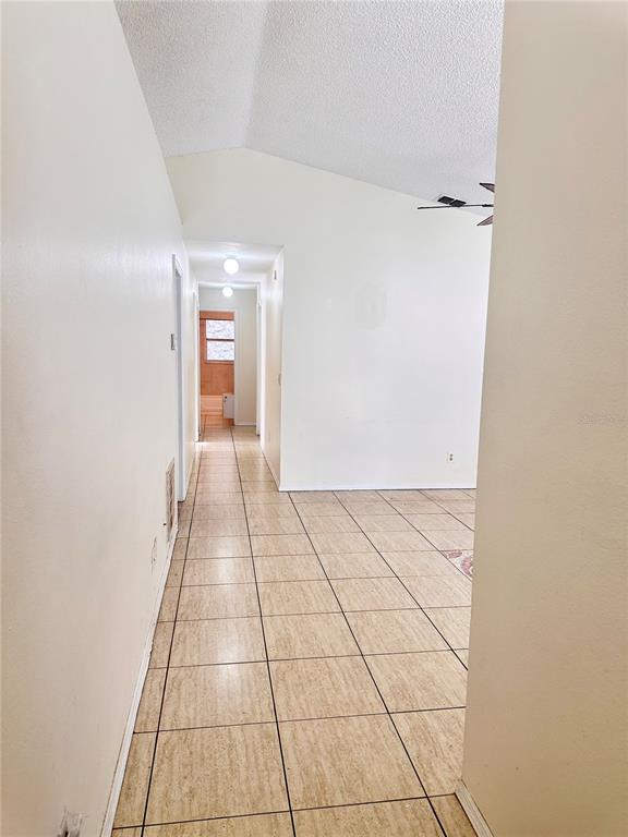 A kitchen with a double sink and white cabinets overlooks a living area with vaulted ceilings — 13706 GLASSER AVENUE, ORLANDO, FL