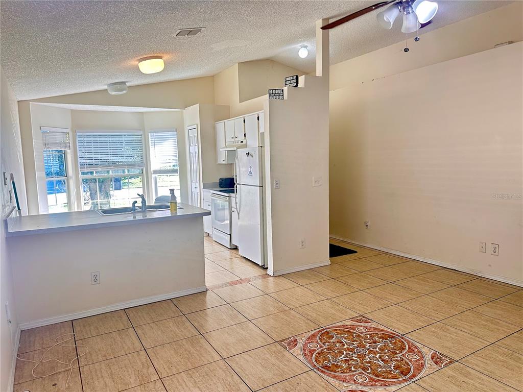 A kitchen features a double-basin sink, tile flooring, and a bay window with blinds — 13706 GLASSER AVENUE, ORLANDO, FL