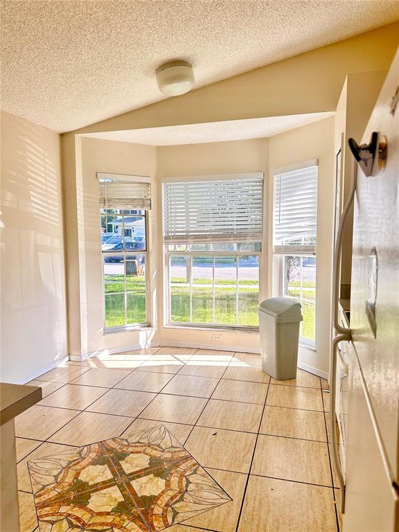 A narrow hallway with light-colored tile flooring leads toward a bathroom with a window — 13706 GLASSER AVENUE, ORLANDO, FL