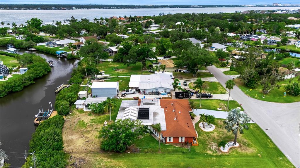 An aerial view shows a residential property with a canal, boat dock, and surrounding neighborhood — 332 SHORE DRIVE, ELLENTON, FL