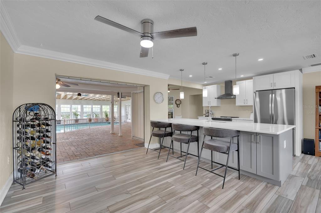 A kitchen with a large island, bar seating, and an open view to a pool area — 332 SHORE DRIVE, ELLENTON, FL