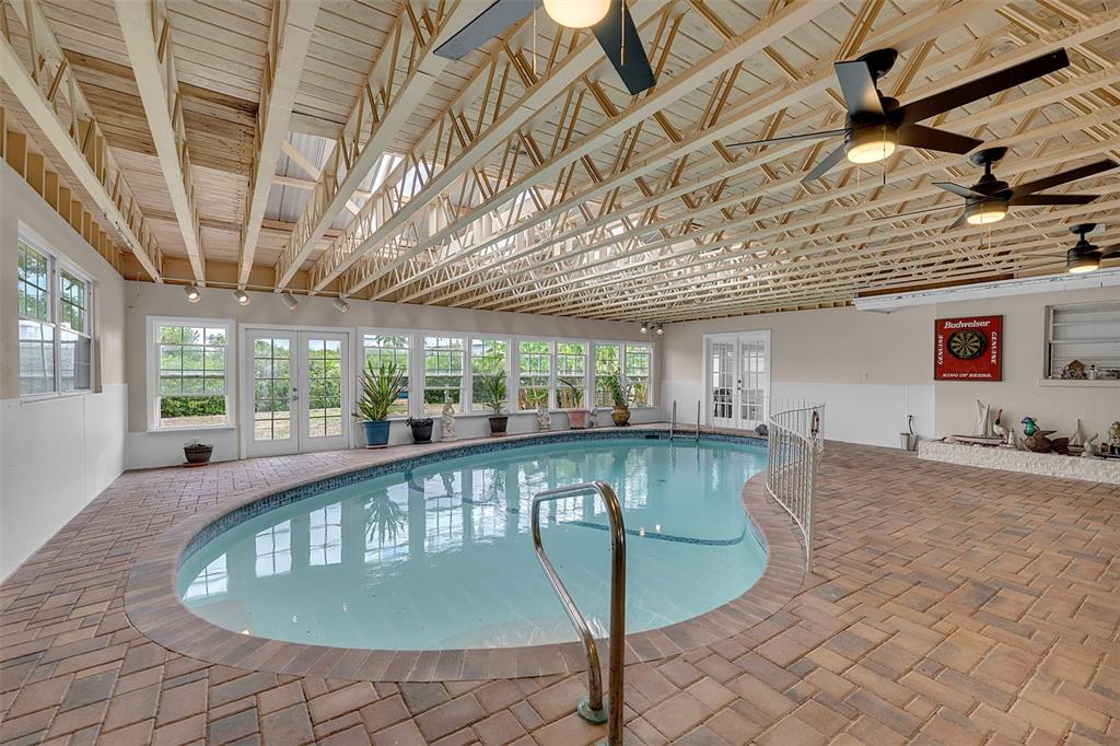 An indoor pool room features a kidney-shaped pool, brick flooring, and an exposed wood ceiling — 332 SHORE DRIVE, ELLENTON, FL