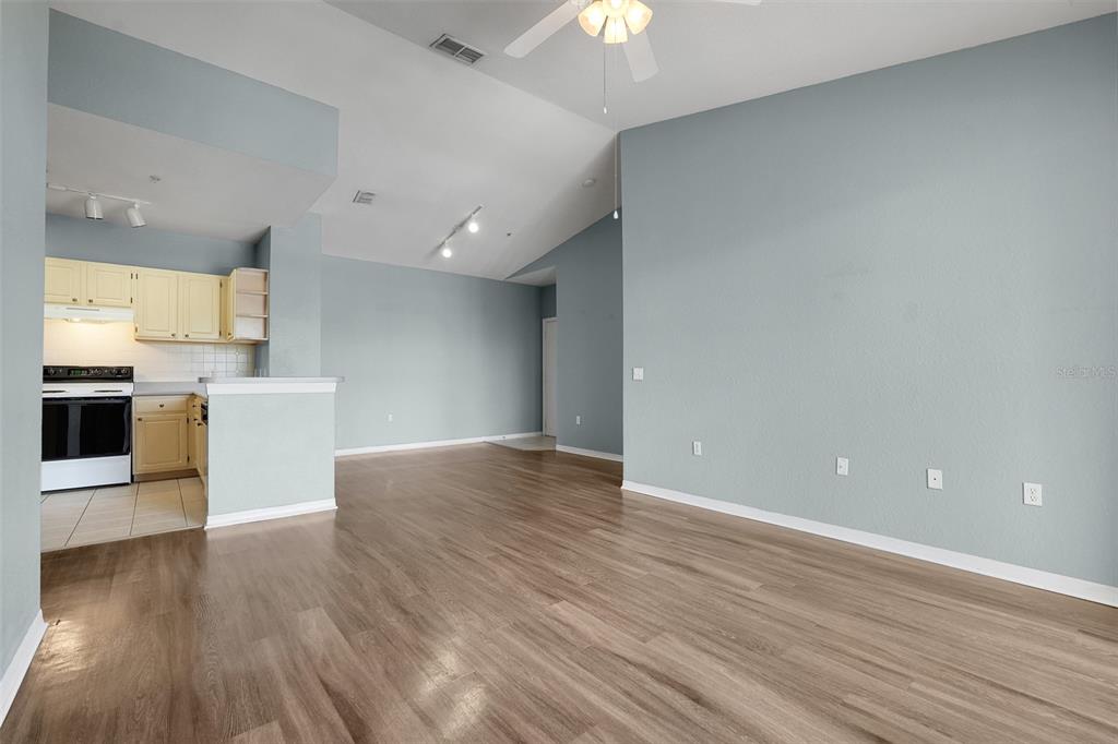An open-concept living area features light blue walls, wood-look flooring, and an adjacent kitchen — 1150 LAKE SHADOW CIRCLE UNIT 3305, MAITLAND, FL