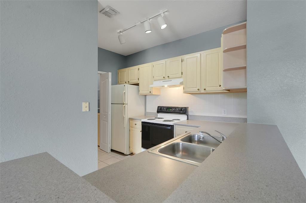 A kitchen features light-colored cabinets, a white refrigerator, a black stove, and a double-basin sink — 1150 LAKE SHADOW CIRCLE UNIT 3305, MAITLAND, FL