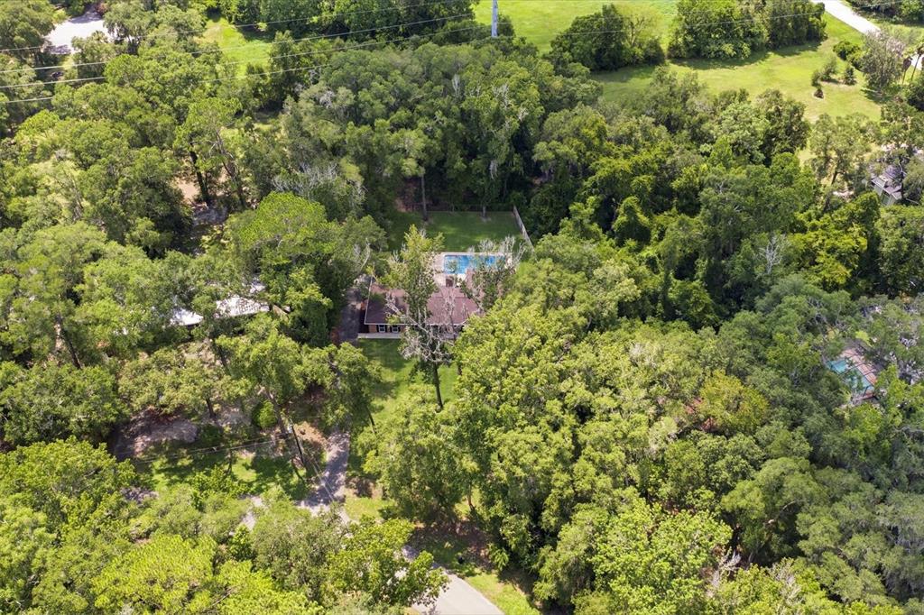 An aerial view shows a house with a swimming pool surrounded by dense green trees — 226 SW 80TH BOULEVARD, GAINESVILLE, FL