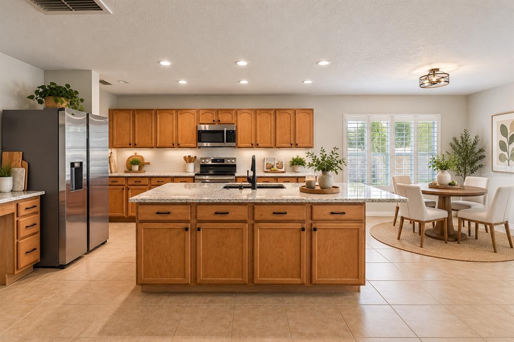 A kitchen features wood cabinets, granite countertops, a central island, and stainless steel appliances — 14759 ROYAL POINCIANA DRIVE, ORLANDO, FL