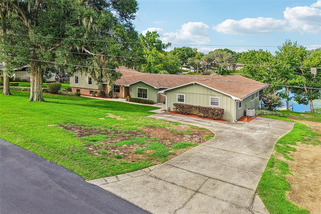 A green, single-story house with a brown shingled roof and a concrete driveway — 1460 GROVE STREET, EUSTIS, FL