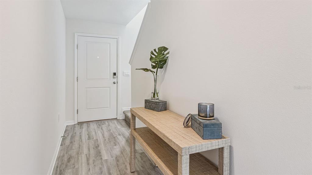 A light-filled entryway features wood-look flooring, a white door, and a wooden console table — 2342 AVEENO AVENUE, HAINES CITY, FL