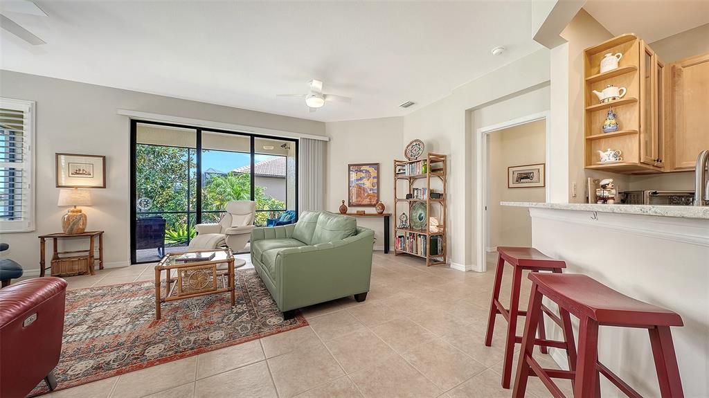 A living room features a green sofa, red bar stools, and a sliding glass door — 1383 MASENO DRIVE, VENICE, FL