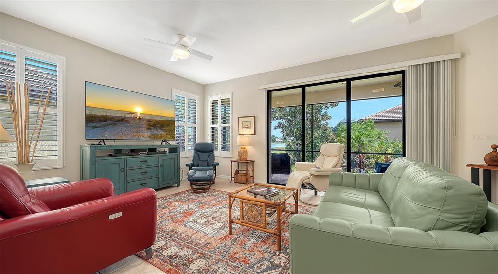 A living room features a red leather chair, a green sofa, and a large television — 1383 MASENO DRIVE, VENICE, FL