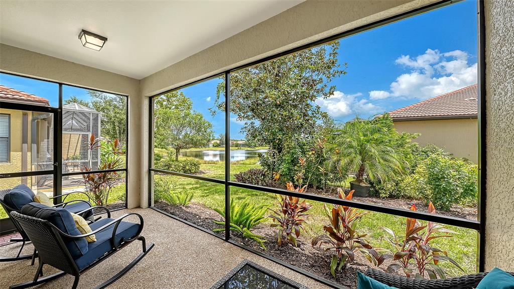 A screened-in patio features dark wicker rocking chairs, a concrete floor, and views of a lake — 1383 MASENO DRIVE, VENICE, FL