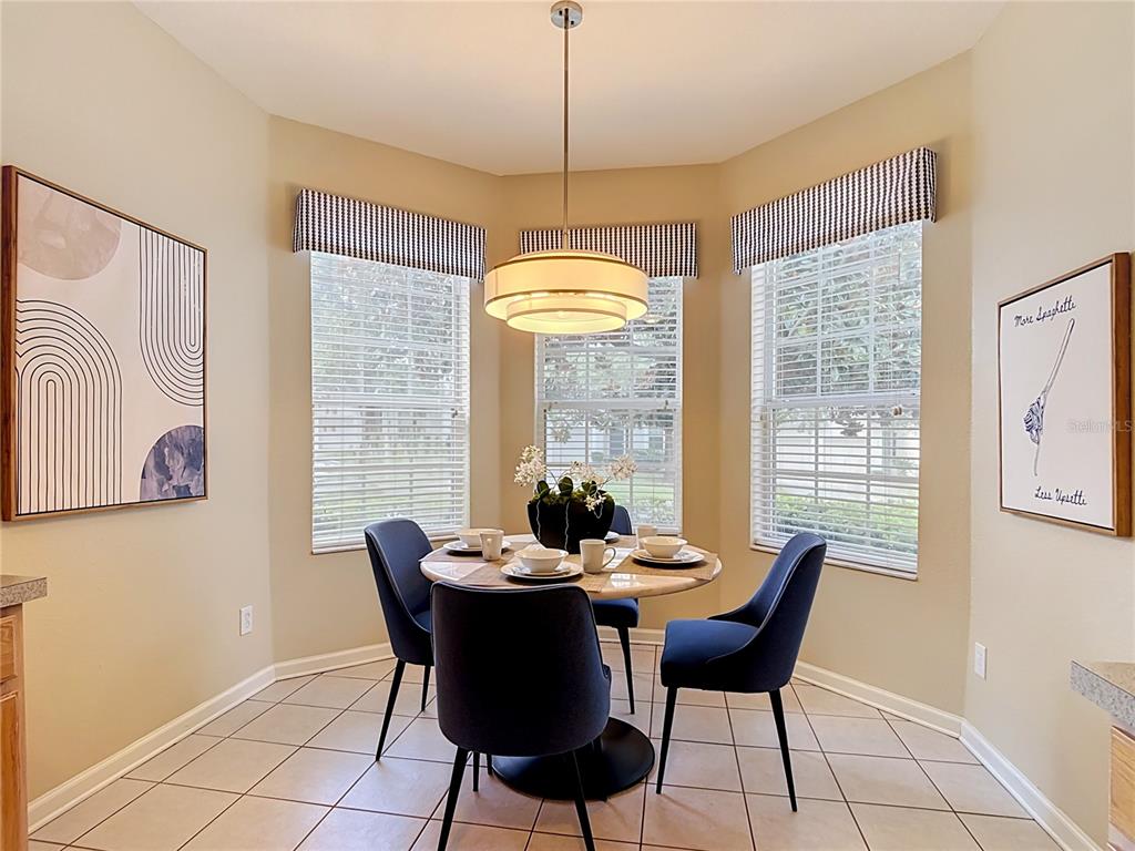A dining nook features a round table with four blue chairs under a pendant light — 7742 COMROW ST, KISSIMMEE, FL