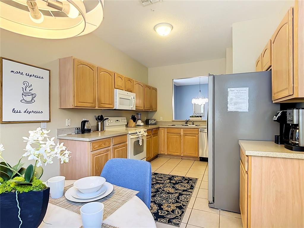 A kitchen features light wood cabinets, stainless steel appliances, and a small dining area — 7742 COMROW ST, KISSIMMEE, FL