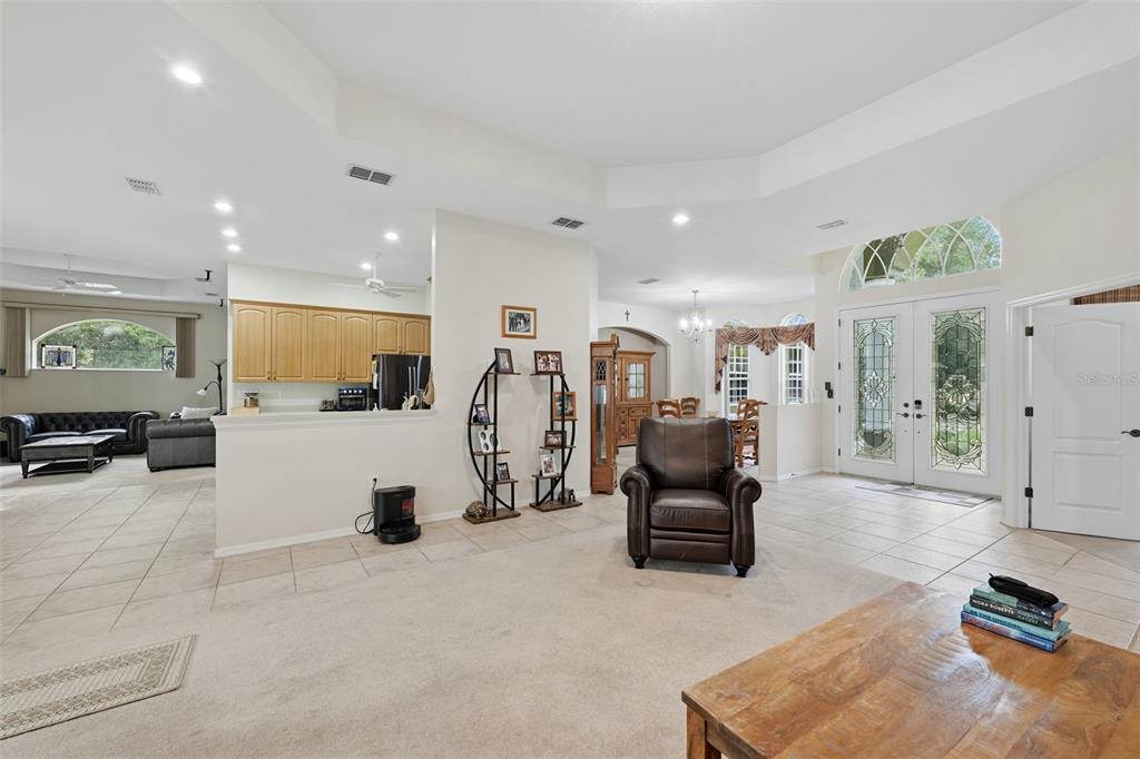 A spacious living area features tile and carpet flooring, a brown leather recliner, and kitchen — 16547 CROSSANDRA LANE, SPRING HILL, FL