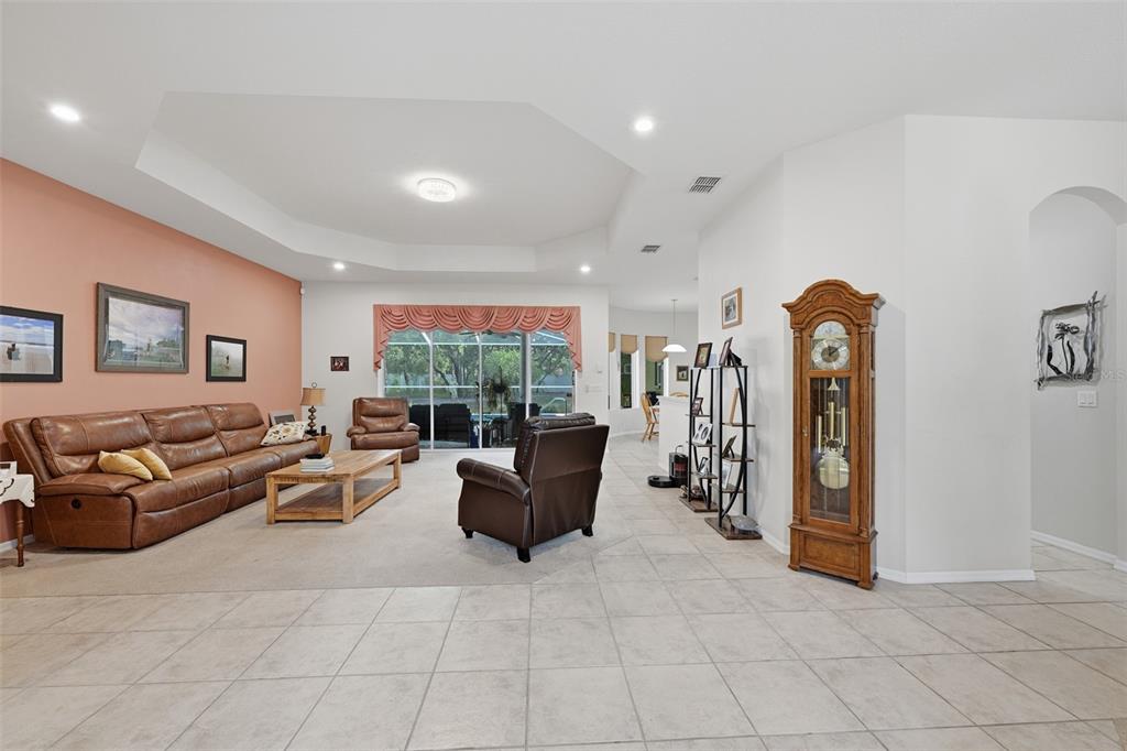 A living room features a brown leather sofa, a grandfather clock, and tile flooring — 16547 CROSSANDRA LANE, SPRING HILL, FL