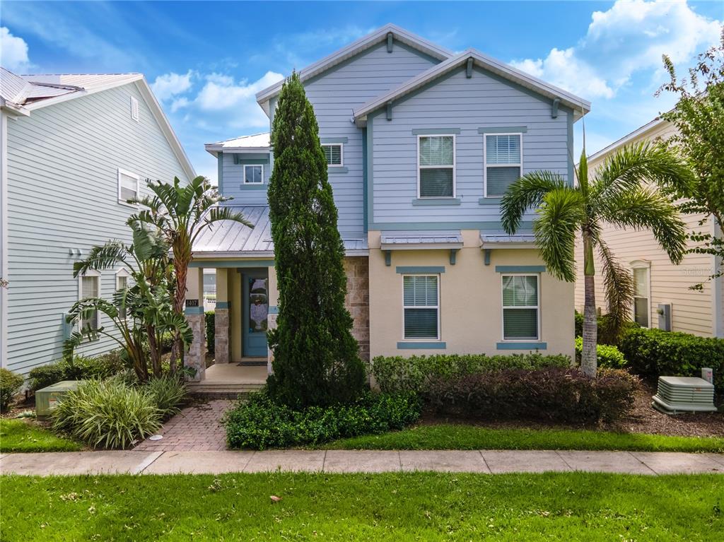 A two-story house with blue siding, stone accents, and a metal roof over the entryway — 1407 FAIRVIEW CIRCLE, REUNION, FL