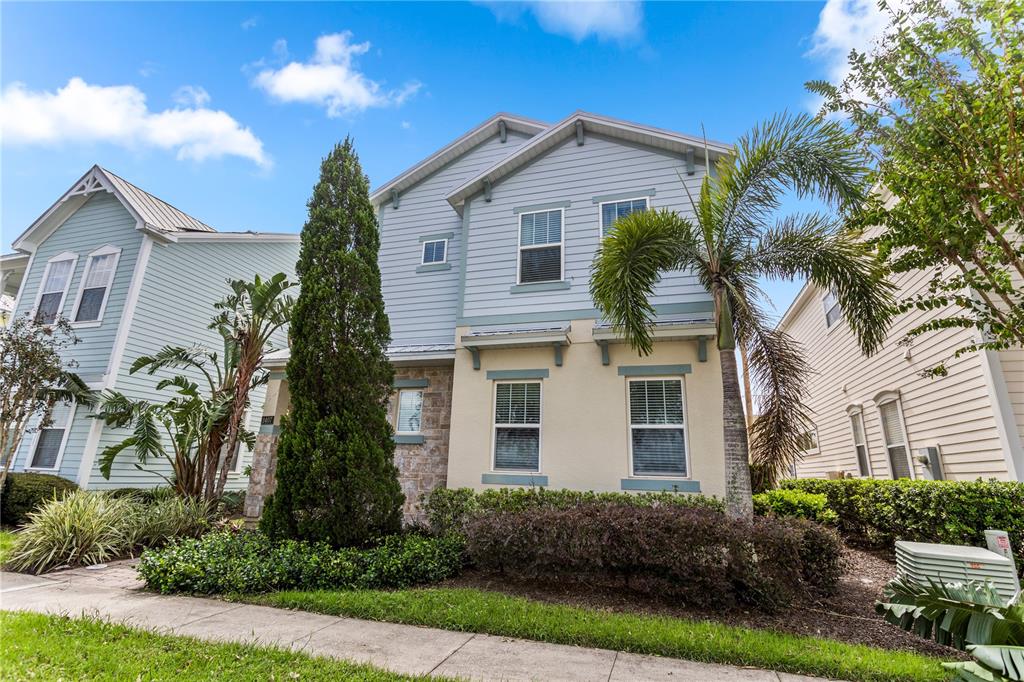 A two-story house with light blue siding, stone accents, and a palm tree in front — 1407 FAIRVIEW CIRCLE, REUNION, FL