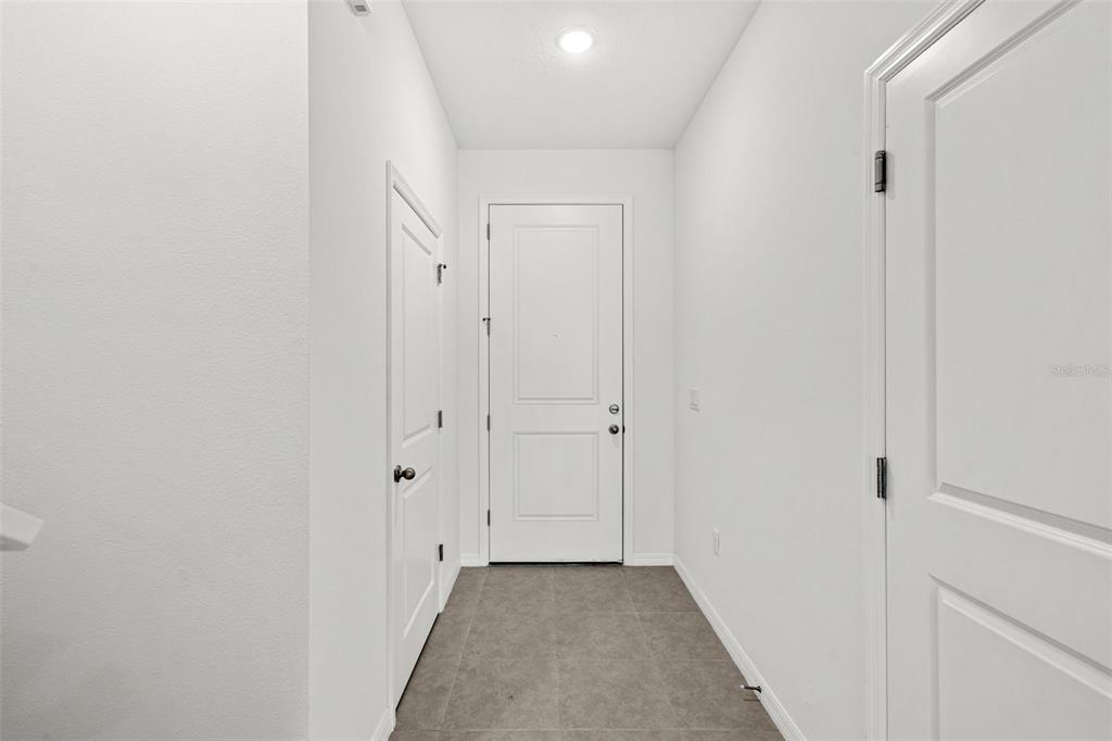 A bright entryway features white walls, a wood-look floor, and three white doors — 4899 WINDING RIVER ROAD, ORLANDO, FL