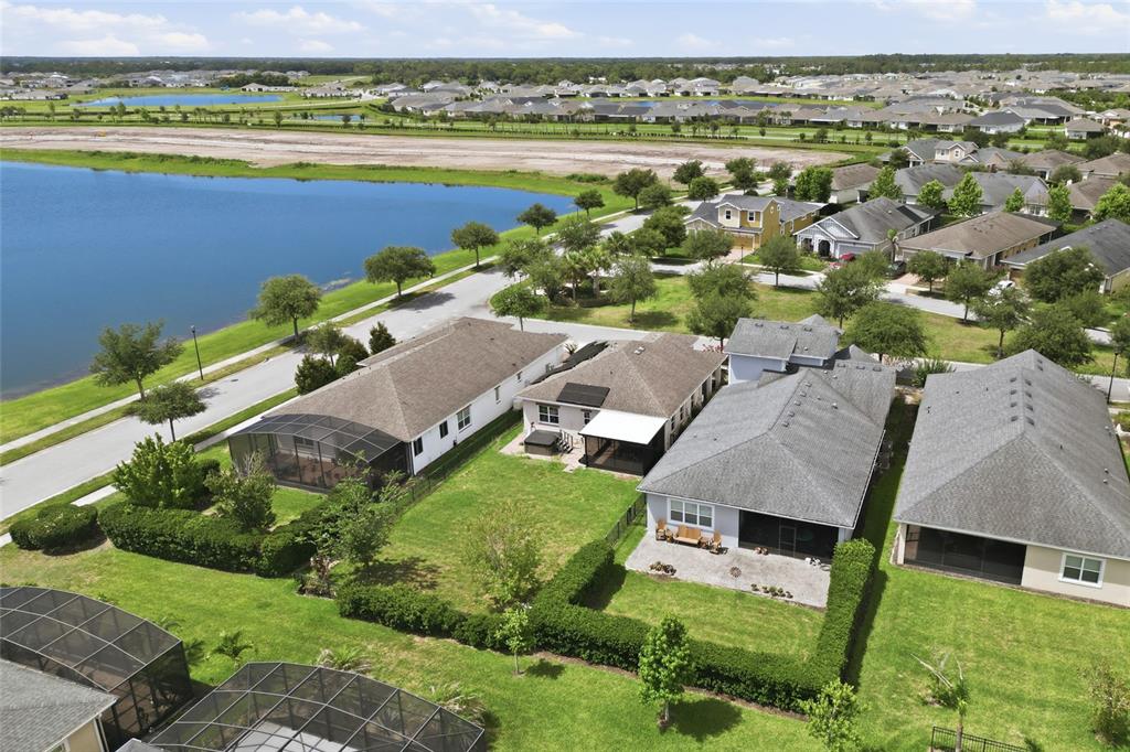 An aerial view shows several suburban houses with screened-in lanais near a large lake — 5027 E FOUNTAINWOOD DRIVE, ST CLOUD, FL