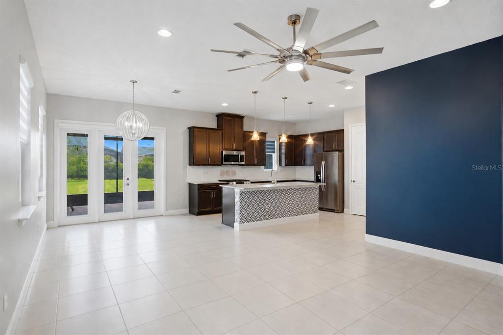 A kitchen with dark wood cabinets, a patterned island, and a blue accent wall — 5027 E FOUNTAINWOOD DRIVE, ST CLOUD, FL