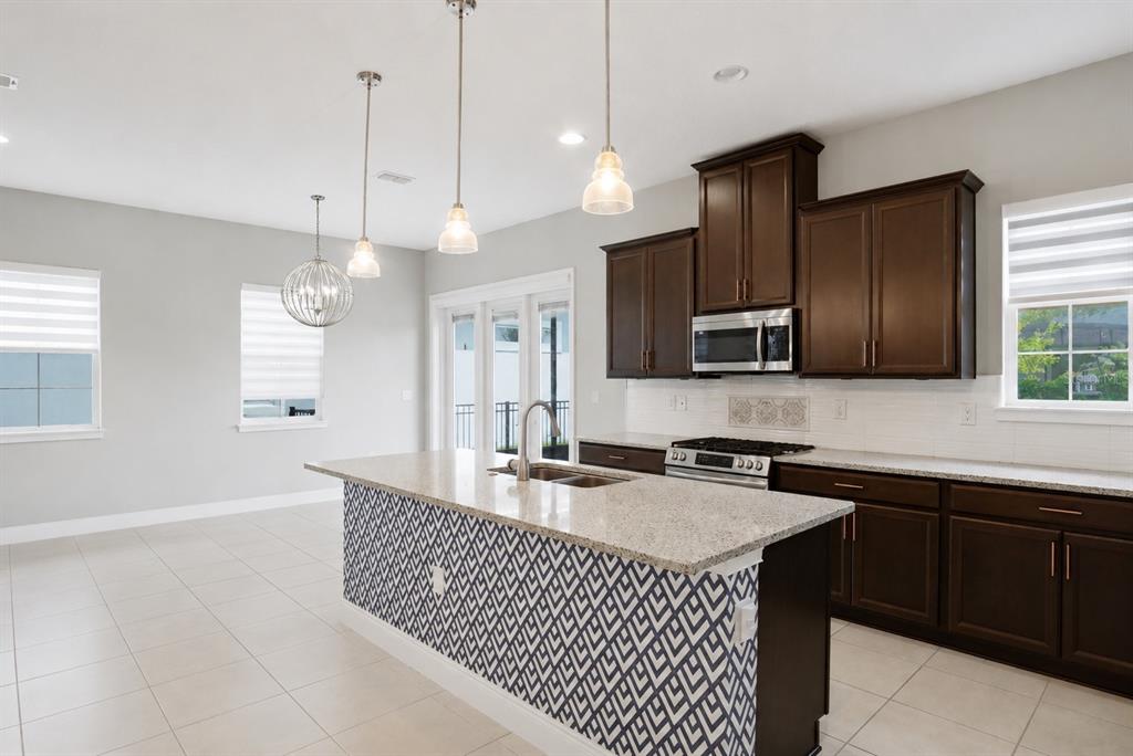 A kitchen features dark wood cabinets, granite countertops, and a patterned island base — 5027 E FOUNTAINWOOD DRIVE, ST CLOUD, FL