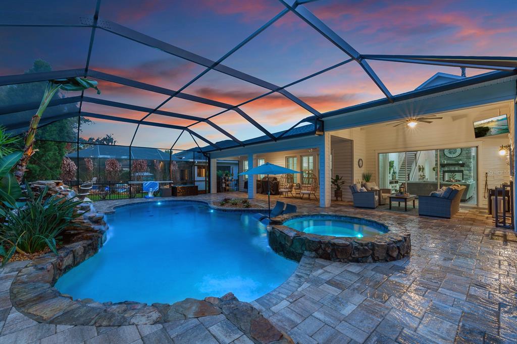 A screened-in patio features a swimming pool, a stone hot tub, and outdoor furniture — 5202 ALAFIA FALLS DRIVE, LITHIA, FL
