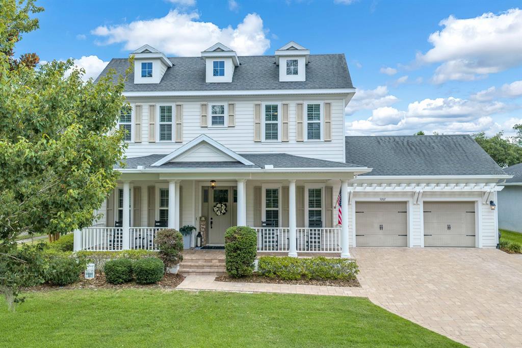 A two-story house with white siding, a front porch, three dormers, and an attached garage — 5202 ALAFIA FALLS DRIVE, LITHIA, FL