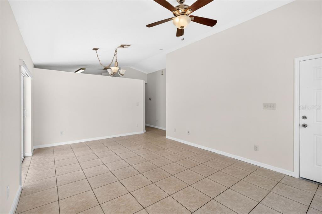 An empty room with beige tile flooring, a ceiling fan, and a white door — 2382 HARBOR TOWN DRIVE, KISSIMMEE, FL