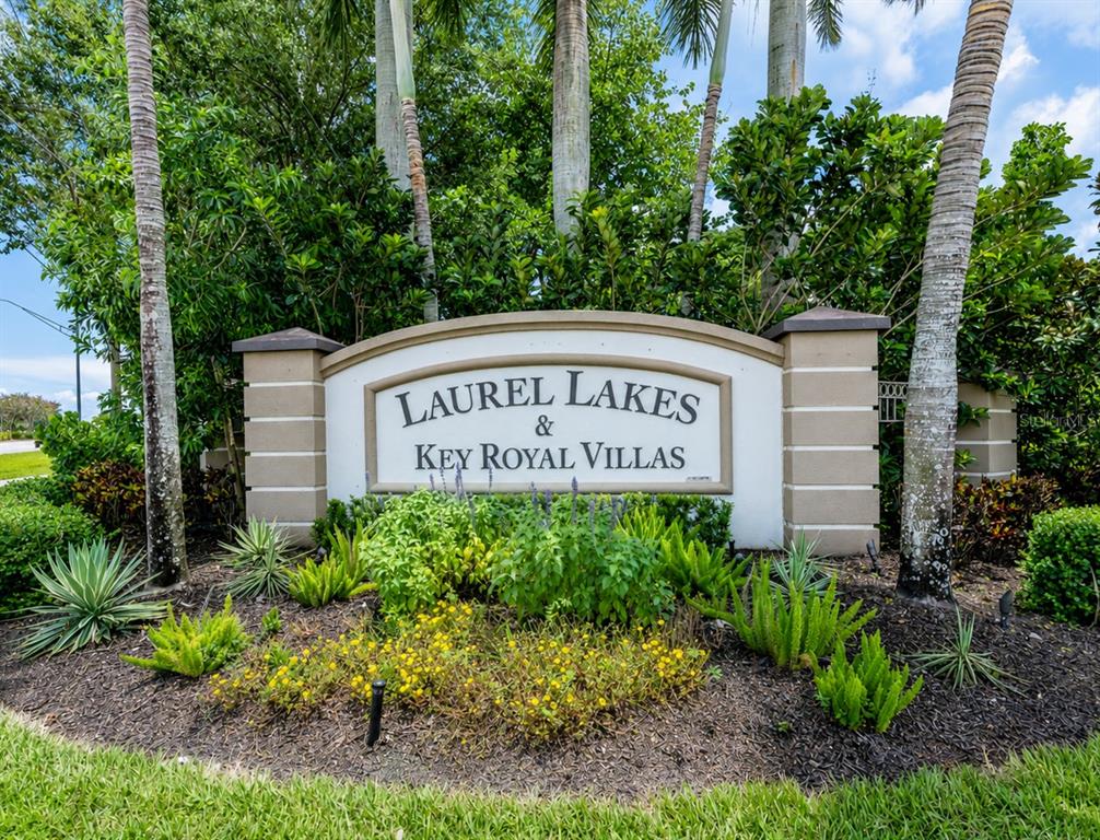 A sign for Laurel Lakes and Key Royal Villas stands in a landscaped garden bed — 8294 KEY ROYAL CIRCLE UNIT 1631, NAPLES, FL