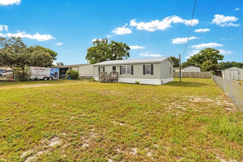 A single-story manufactured home sits on a large, grassy lot under a blue sky — 5055 TRANSPORT ROAD, BARTOW, FL