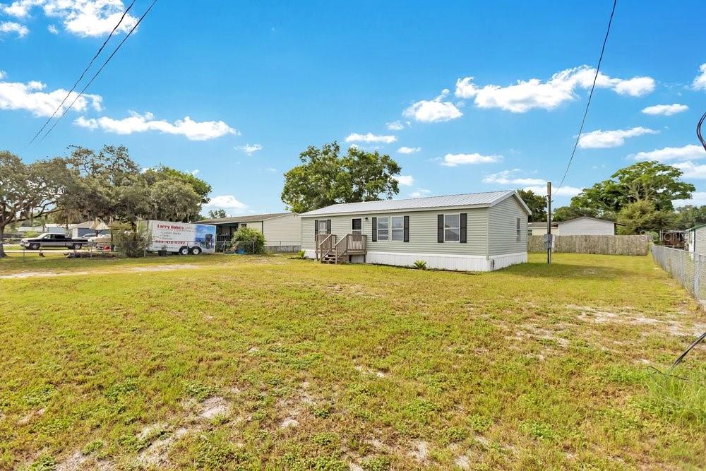 A light green manufactured home sits on a large, grassy lot under a blue sky — 5055 TRANSPORT ROAD, BARTOW, FL