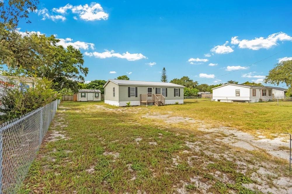 A light green manufactured home sits on a large, grassy lot with a small shed — 5055 TRANSPORT ROAD, BARTOW, FL