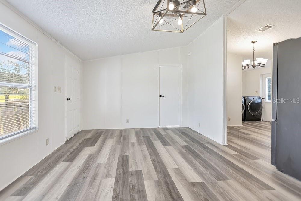 A bright room with white walls, wood-look vinyl flooring, and a modern geometric light fixture — 5055 TRANSPORT ROAD, BARTOW, FL