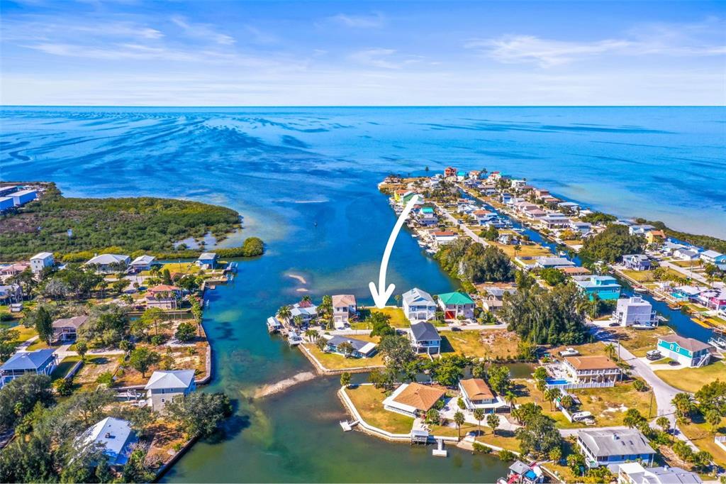 An aerial view shows a waterfront residential property marked by a white arrow — MCDONALD LN, HUDSON, FL