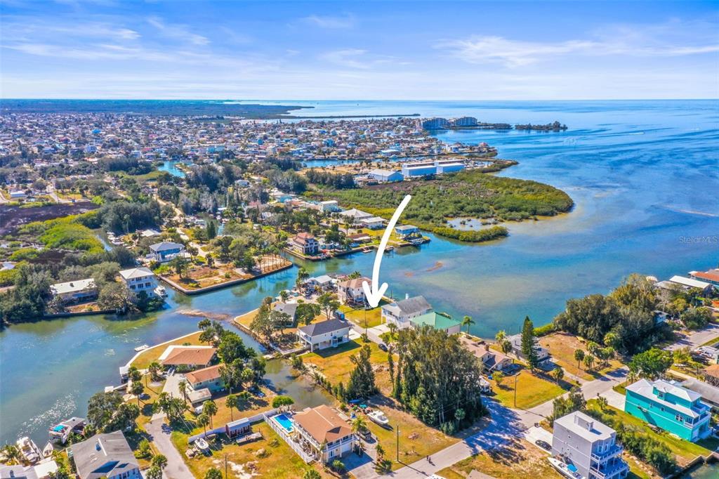 An aerial view shows a waterfront house with a white arrow pointing toward it — MCDONALD LN, HUDSON, FL