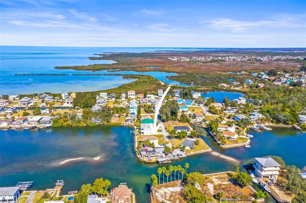 An aerial view shows a waterfront house with a white arrow pointing toward it — MCDONALD LN, HUDSON, FL