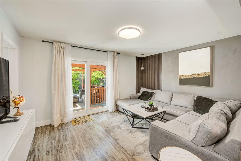 A living room features a gray sectional sofa, wood-look flooring, and sliding glass doors to a deck — 11288 60TH AVENUE, SEMINOLE, FL
