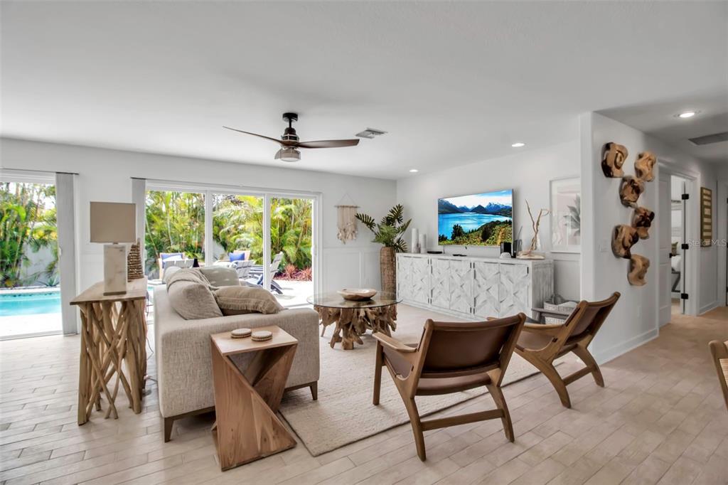 A living room features a beige sofa, two leather chairs, a wood coffee table, and sliding doors — 207 PEACOCK LANE, HOLMES BEACH, FL